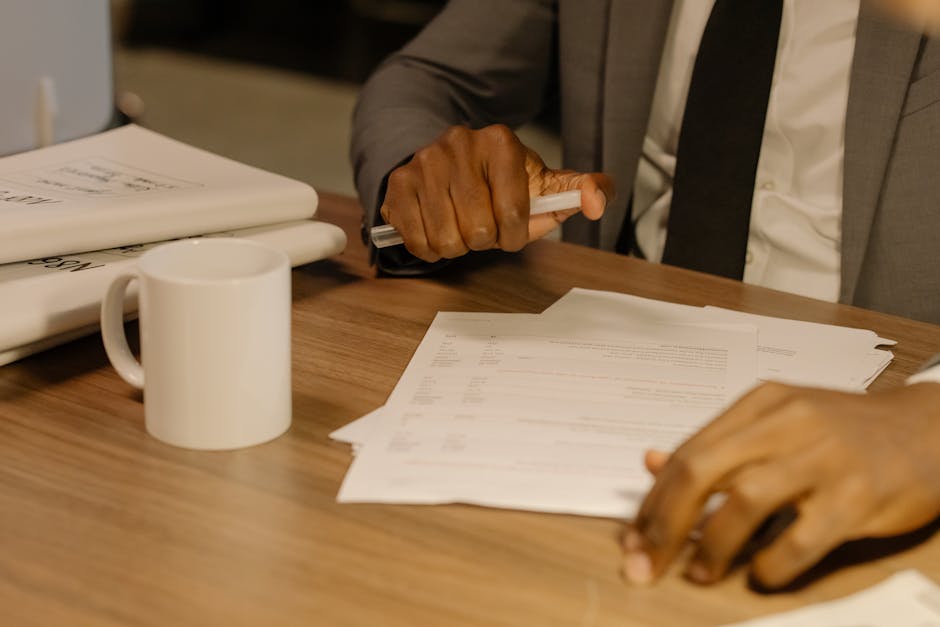 Manos revisando documentos sobre mesa de madera con luz lateral